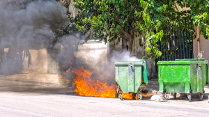 Waste-container-on-wheels-set-on-fire-emitting-smoke-Shutterstock