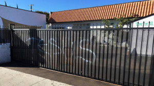 This photo provided by the Ahmadiyya Muslim Community muslimsforpeace.org shows "Jesus" in spray paint vandalizing a gate at the Ahmadiyya Muslim Community Baitus-Salaam Mosque in Hawthorne, Calif., Sunday, Dec. 13, 2015. The FBI is investigating after police in Hawthorne say two mosques in that city were vandalized with paint, and a fake grenade was left in the driveway of one of the properties.(Ahmadiyya Muslim Community muslimsforpeace.org via AP)
